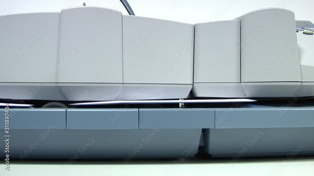 Franking machine through in a stack of enveloped letters one by one to apply postage - very close detail shot. Franking machine through in a stack of enveloped letters one by one to apply postage - very close detail shot.