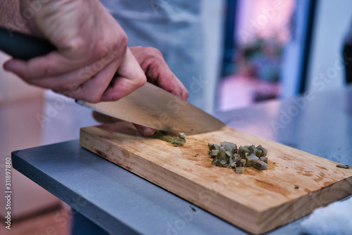 Chopping a fresh artichoke on a wooden kitchen board. Adult men hands.Chopping a fresh artichoke on a wooden kitchen board. Adult men hands. kitchen healthy life style
