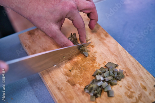 Chopping a fresh artichoke on a wooden kitchen board. Adult woman hands. kitchen healthy life style