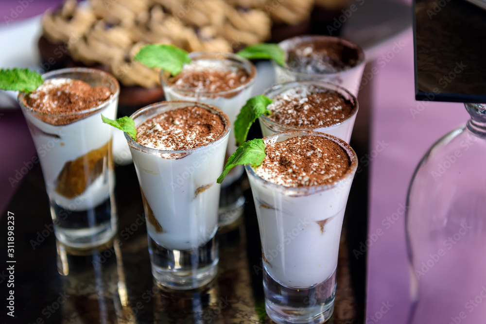 Sweet vanilla mousse with cocoa and mint, portioned dessert in glass cups. Catering, restaurant service. Sweet vanilla mousse with cocoa and mint, portioned dessert in glass cups. Catering, restaurant service.