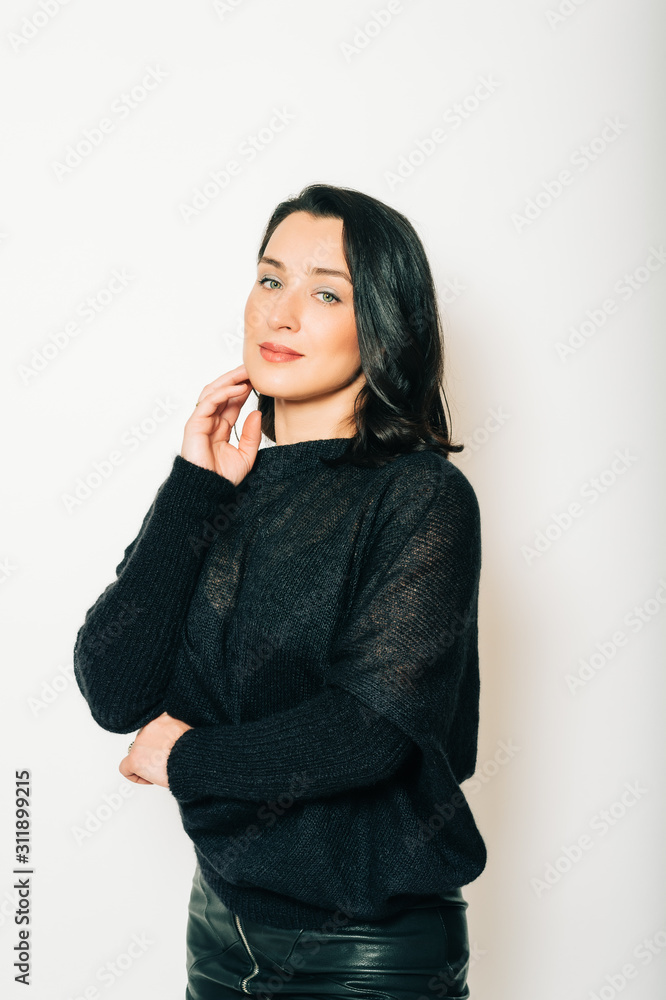 Studio portrait of beautiful brunette woman wearing black pullover, posing on white background Studio portrait of beautiful brunette woman wearing black pullover, posing on white background
