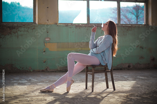 Ginger, blonde ballerina sitting on the chair smoking. Sport and smoking concept