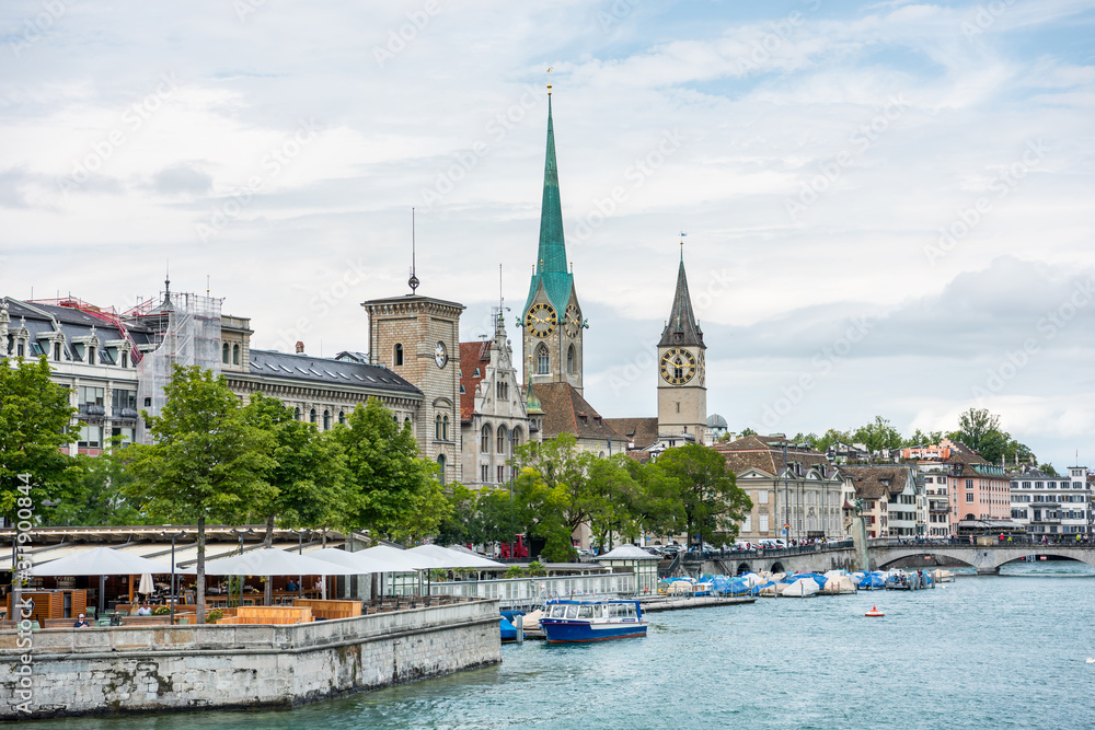 View of the historic buildings and bridge of Zurich at the bank of Limmat River and Zurich lake, with landmark of Fraumünster Church clock tower and church  tower of St. Peter Pfarrhaus