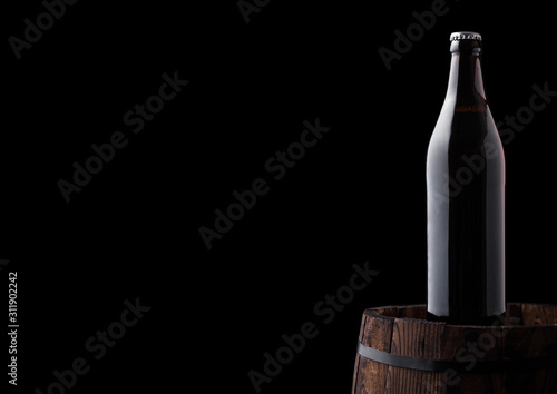 Cold bottle of craft beer on old wooden barrel