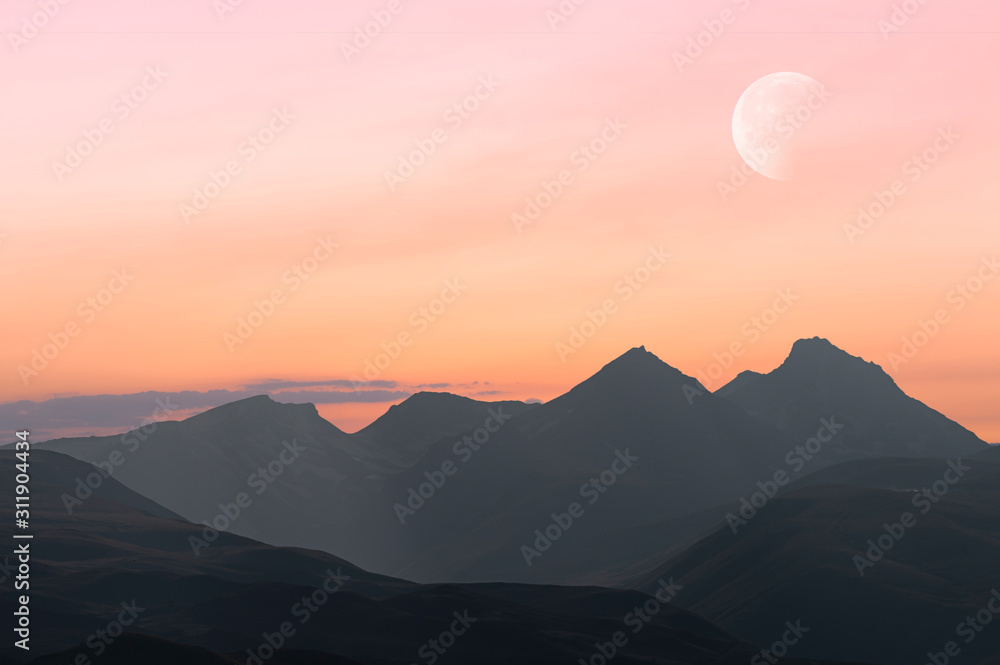 Beautiful landscape, mountains on the sunset. Colorful orange sky and moon.