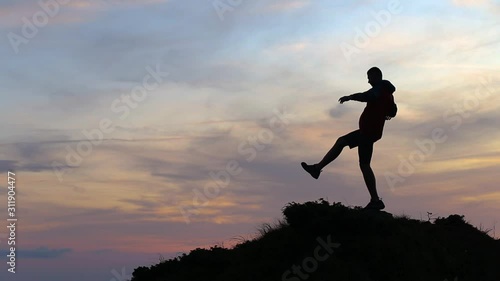 Wallpaper Mural Dark silhouette of a hiker balancing on a stone in evening mountains. Torontodigital.ca
