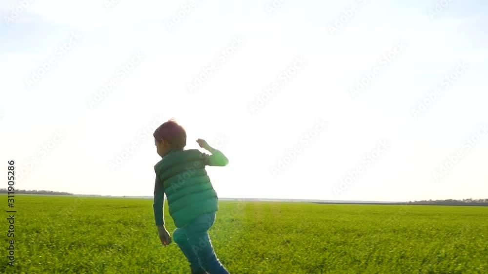 A happy child plays, running on a green field or meadow and launches a toy plane into the sky. A happy child plays, running on a green field or meadow and launches a toy plane into the sky.