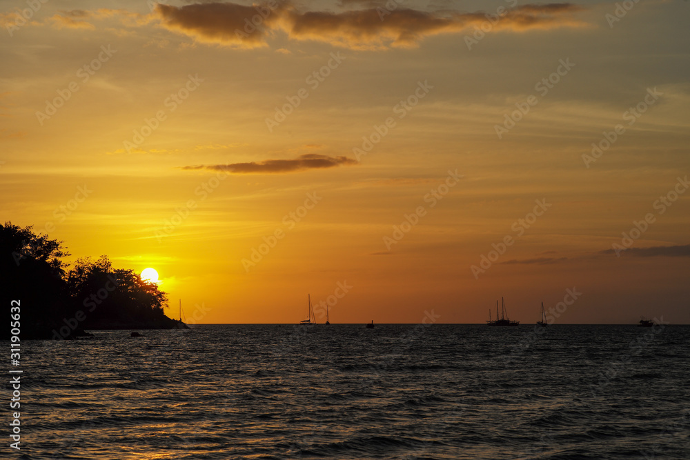 Silhouette of island and yacht boats on the horizontal line with light of sunset and twilight sky in background