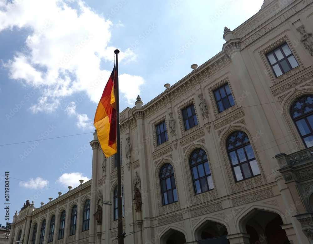 Obraz premium Germany flag on flagpole before facade of Five Continents Museum in Munich on bright sunny day