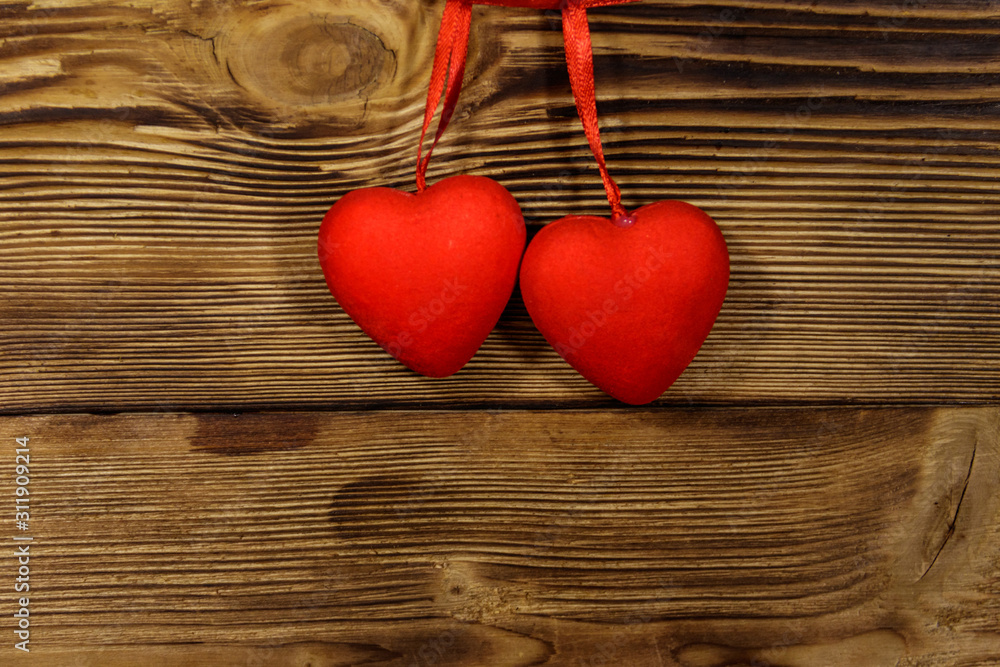 Two red hearts hanging over wooden background Two red hearts hanging over wooden background