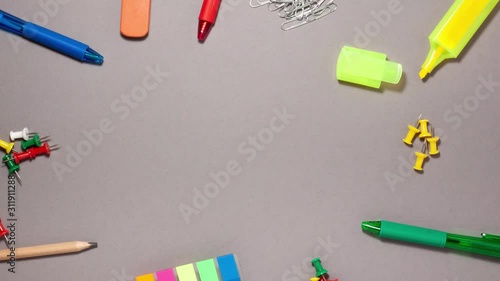 Pen, sticky note, marker, eraser, push pins, paperclip on gray background. Stop motion animation flat lay top view. Education and back to school concept.