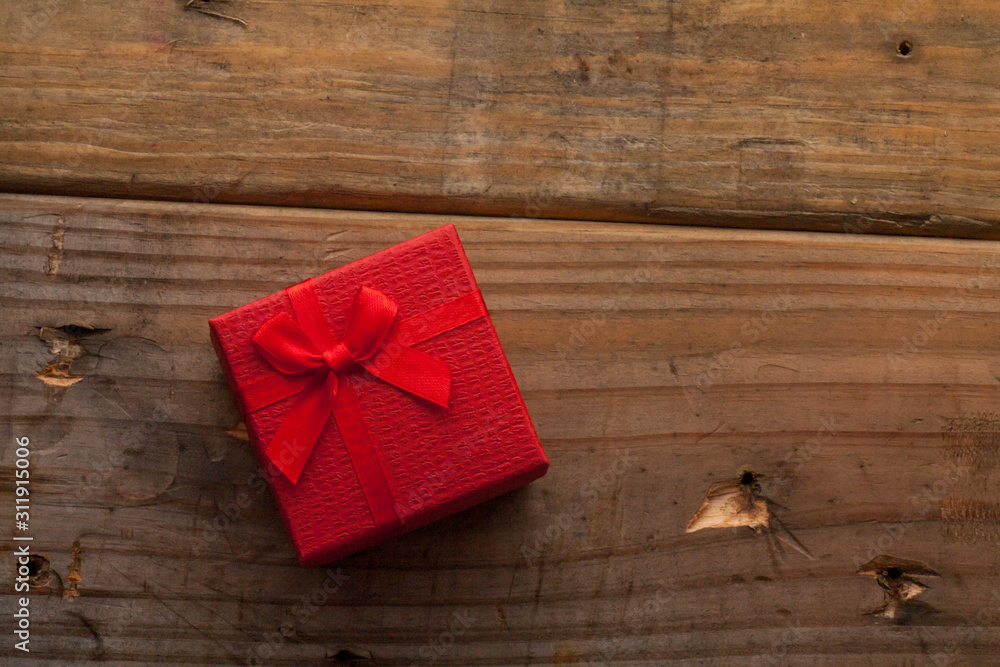 Red color gift box with bow on wooden background Red color gift box with bow on wooden background