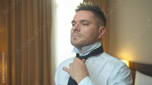 Man put on tie in room of the hotel