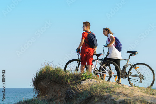 boy and young woman on a Bicycle on a cliff by the sea