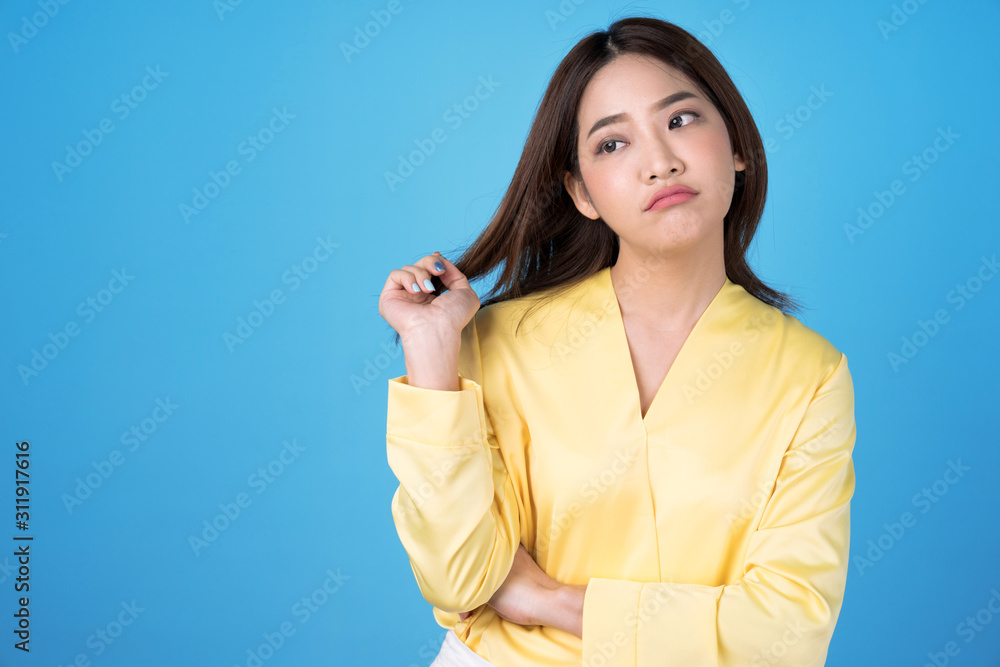 Portrait of an upset unsatisfied asian woman standing isolated on blue background. Portrait of an upset unsatisfied asian woman standing isolated on blue background.