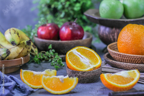 Photo of fresh orange on retro background. Slice of orange in front of fruits and vegetables. Half of the orange on wooden plate bowl. Sunkist. Summer. Image