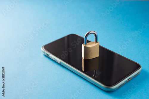 Personal data protection concept in the phone, smartphone and metal lock on a blue background