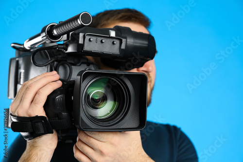 Operator with professional video camera on blue background