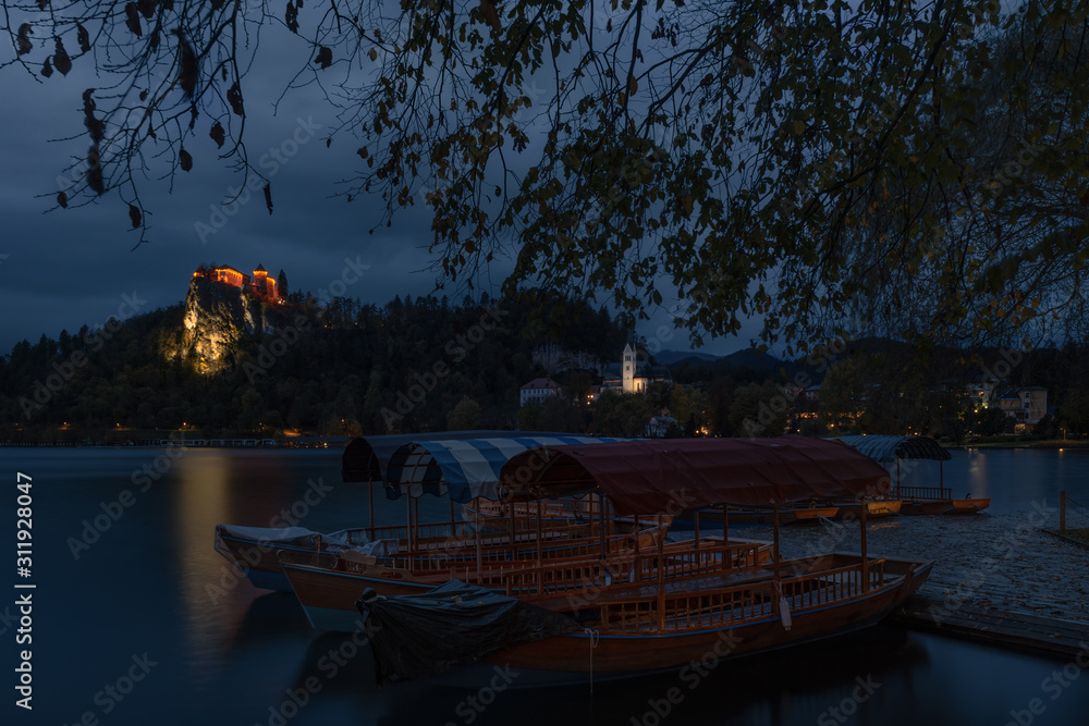 The Pearl Of Slovenia's Nature, Amazing Lake Bled,Late Autumn. Early Morning With Overcast Sky And View Of The Bled Castle (Blejski Grad) And Marina With «Pletna» - Traditional Boats Such As Gondolas.
