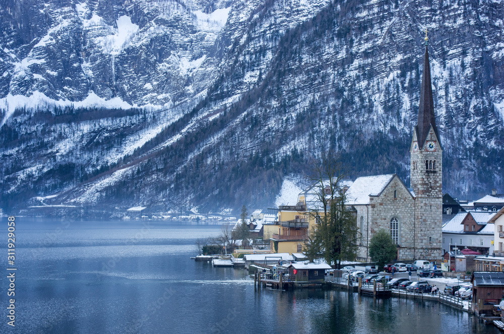 Morning view of cottages of Hallstatt down the foggy mountains with snow on the trees in winter