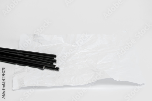 A lot of black pencils lie on a table on a crumpled piece of paper. On white background