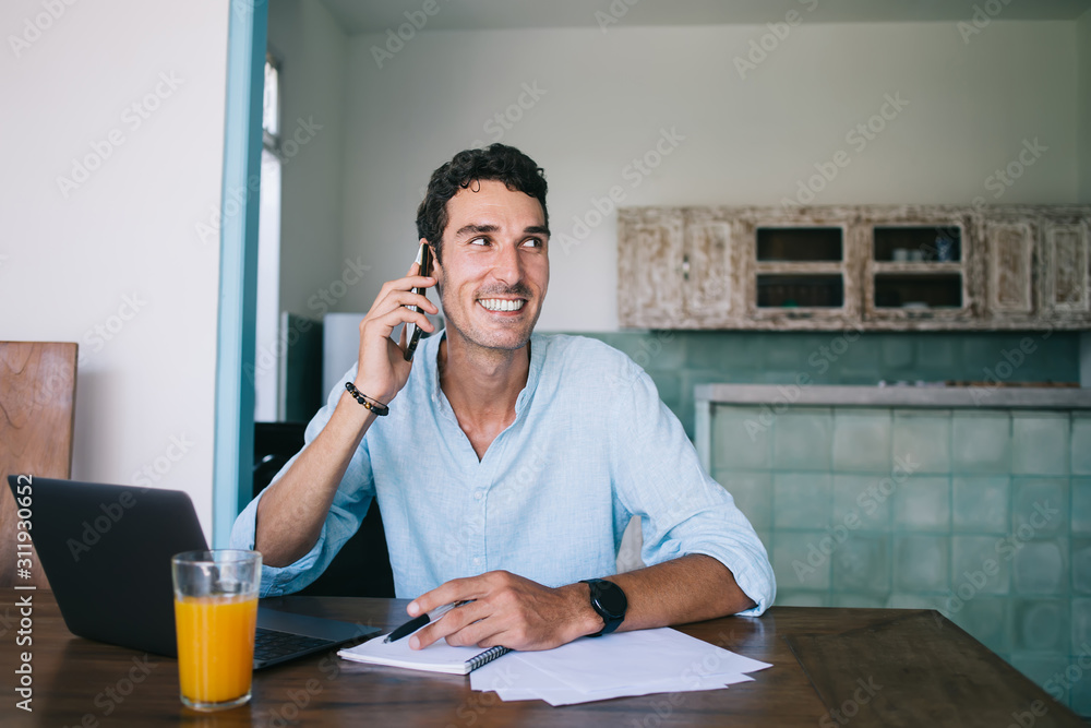 Cheerful adult man talking on smartphone at table Cheerful adult man talking on smartphone at table