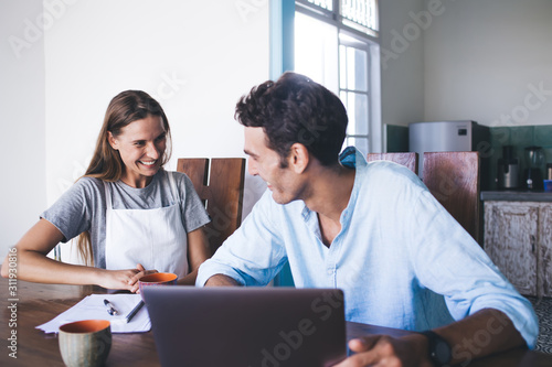 Happy and laughing couple in living room with laptop