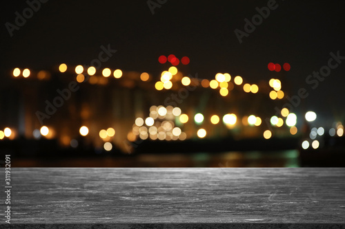 Empty grey stone surface and blurred view of night city. Bokeh effect