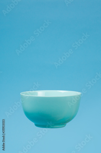 A blue ceramic mattle deep bowl for breakfast flying on blue background. photo