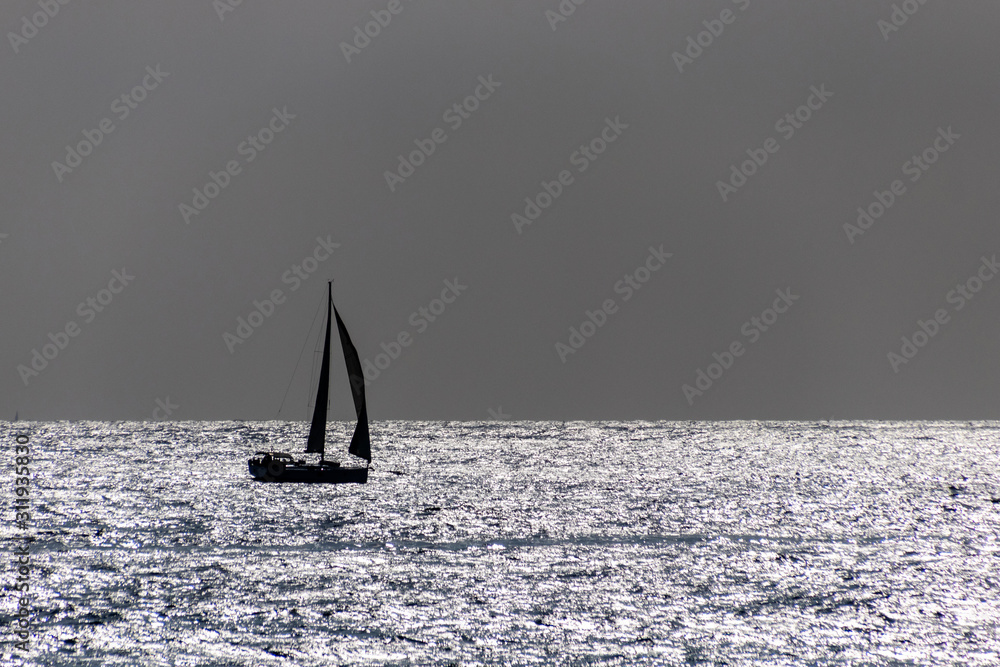 A single boat sailing at the horizont deep in the ocean - romantic scene