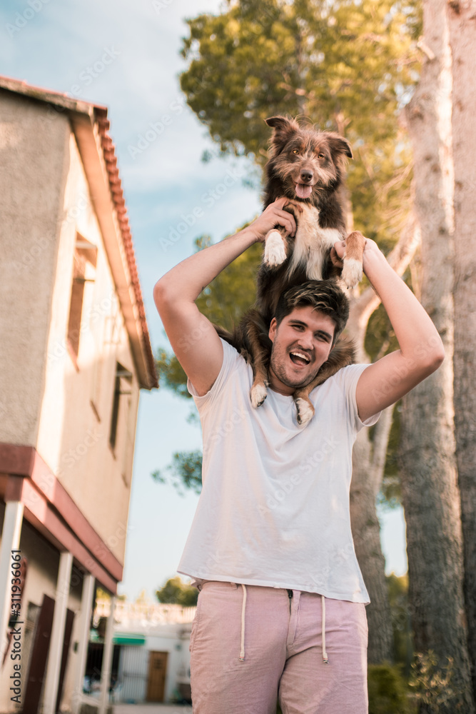 Stock vertical photo of a young boy lifting a dog in the house, happy young boy.