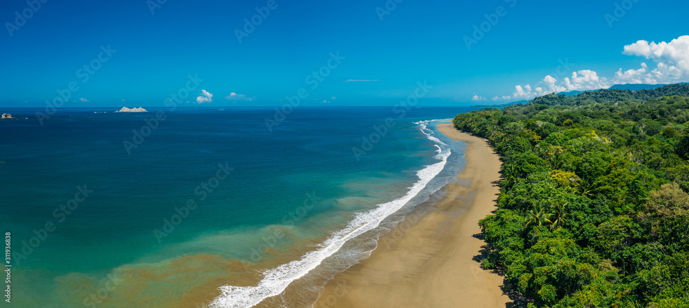 Aerial Drone View of a tropical beach in Costa Rica. Sand and water surrounded by lush rainforest