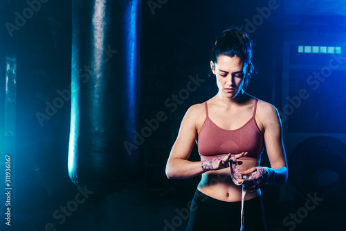 pretty young woman wrapping her hands with boxing hands tape - fight, sport and boxing themes