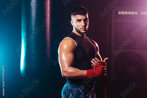 young and muscular man wrapping his hands with boxing hands tape - fight, sport and boxing themes