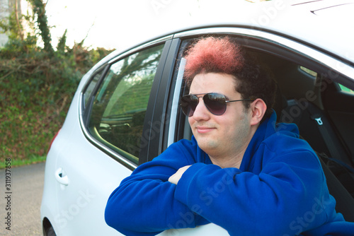 Young man waiting in a car with his head off, admiring the landscape, with sunglasses