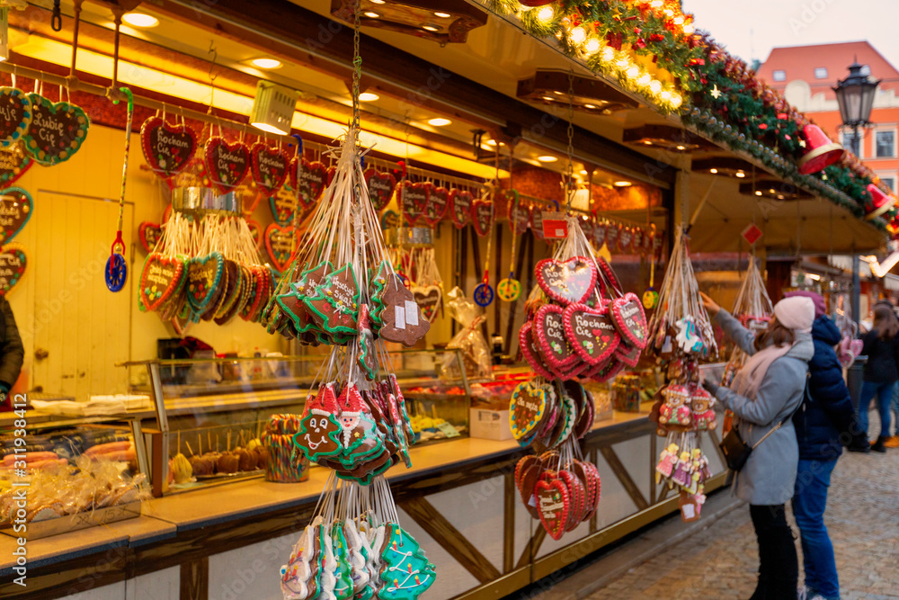 Young woman walking on Christmas market in Europe on holidays. Gingerbread shop and Christmas toys at Xmas Market
