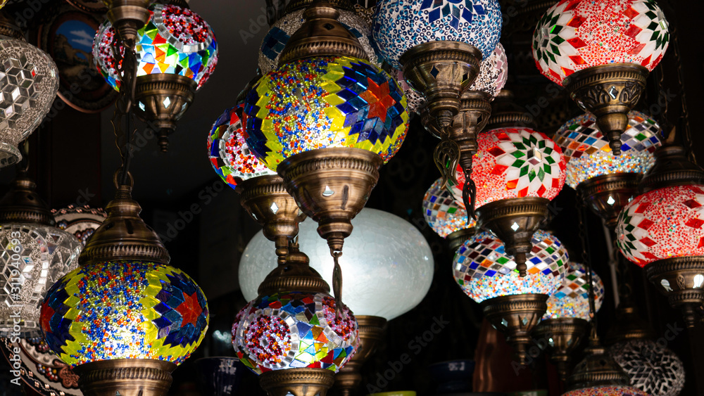Traditional colorful handmade Turkish lamps and lanterns hanging in souvenir shop for sale.