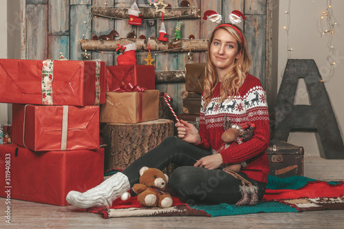 Young pretty girl in a New Year's image among the gifts and holiday decorations