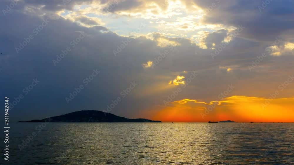 Shining sea with the Burgazada Island at sunset in Istanbul, Turkey. Sparkling sunlight and light rays over the calm water. Color graded in Pana Cine-like Dynamic range Shining sea with the Burgazada Island at sunset in Istanbul, Turkey. Sparkling sunlight and light rays over the calm water. Color graded in Pana Cine-like Dynamic range
