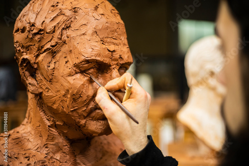 Obraz na plátně Hand of sculptor finishing a clay head eye