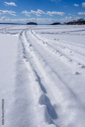 winter scene of ski tracks in snow on frozen lake