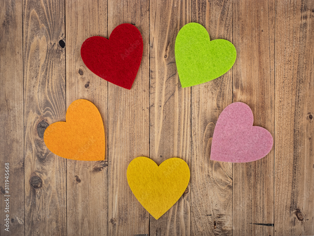 coloured hearts forming a circle on a walnut wood background. Concept of St. Valentine's Day coloured hearts forming a circle on a walnut wood background. Concept of St. Valentine's Day