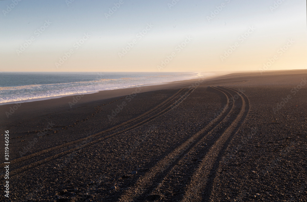 Late afternoon. Ocean beach with tire track in the sand.Akaroa, New Zealand.