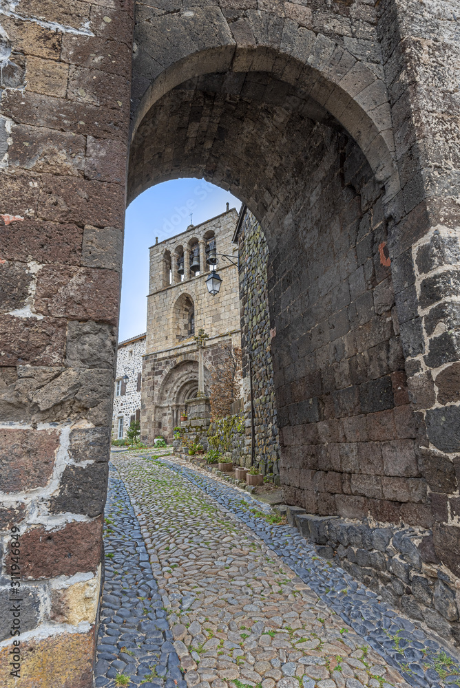 Naklejka premium The entrance to Arlempdes medieval village, the paved walk pass guides to Saint-Pierre roman church, Haute-Loire in France,