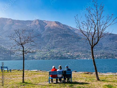 Three pensioned seated on a bench in Lake Como