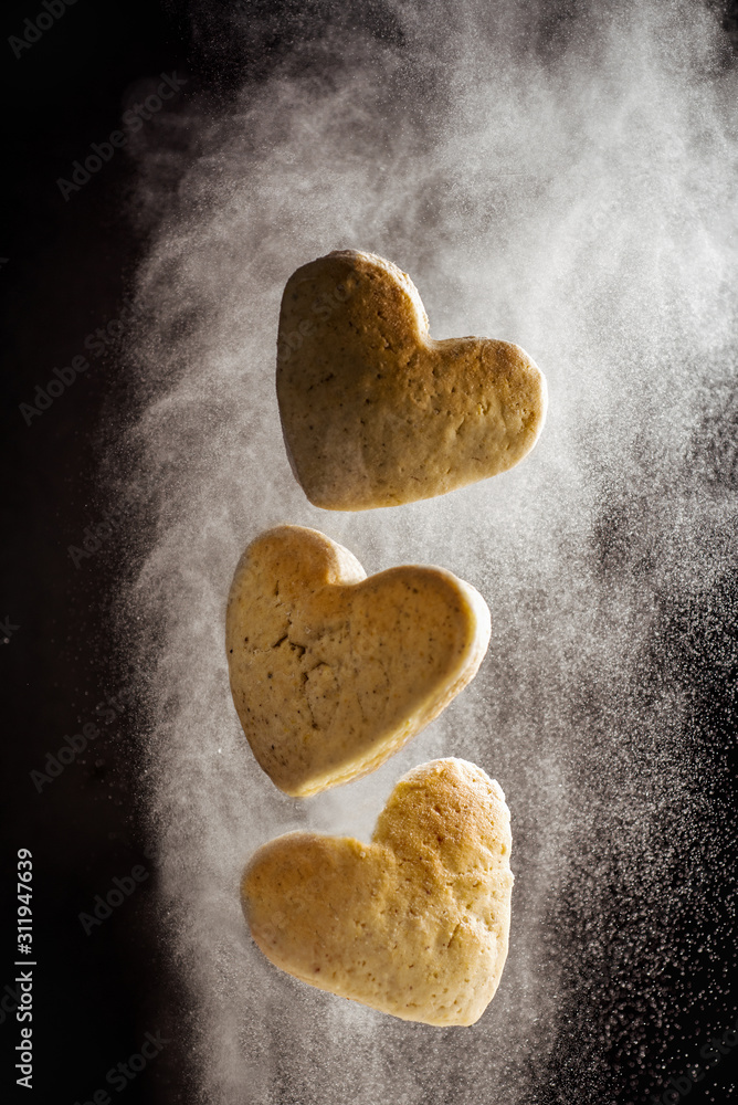 Obraz premium levitate heart shape cookies flying in flour cloud