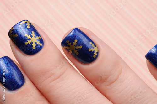 Winter blue manicure with shimmer and snowflakes pattern on red lines candy background