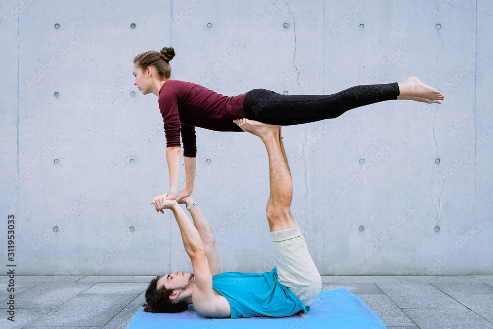 Couple practicing acro yoga outdoors. Acroyoga concept. Front Bird pose.  Asana for beginers Stock Photo