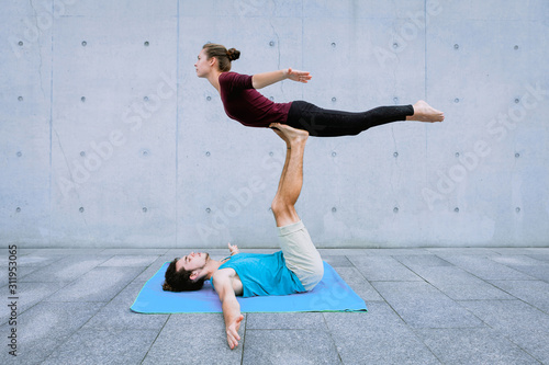Couple practicing acro yoga outdoors. Acroyoga concept. Front Bird pose photo