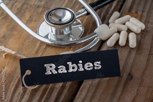 Rabies written on label tag with pills and Stethoscope on wood background photo